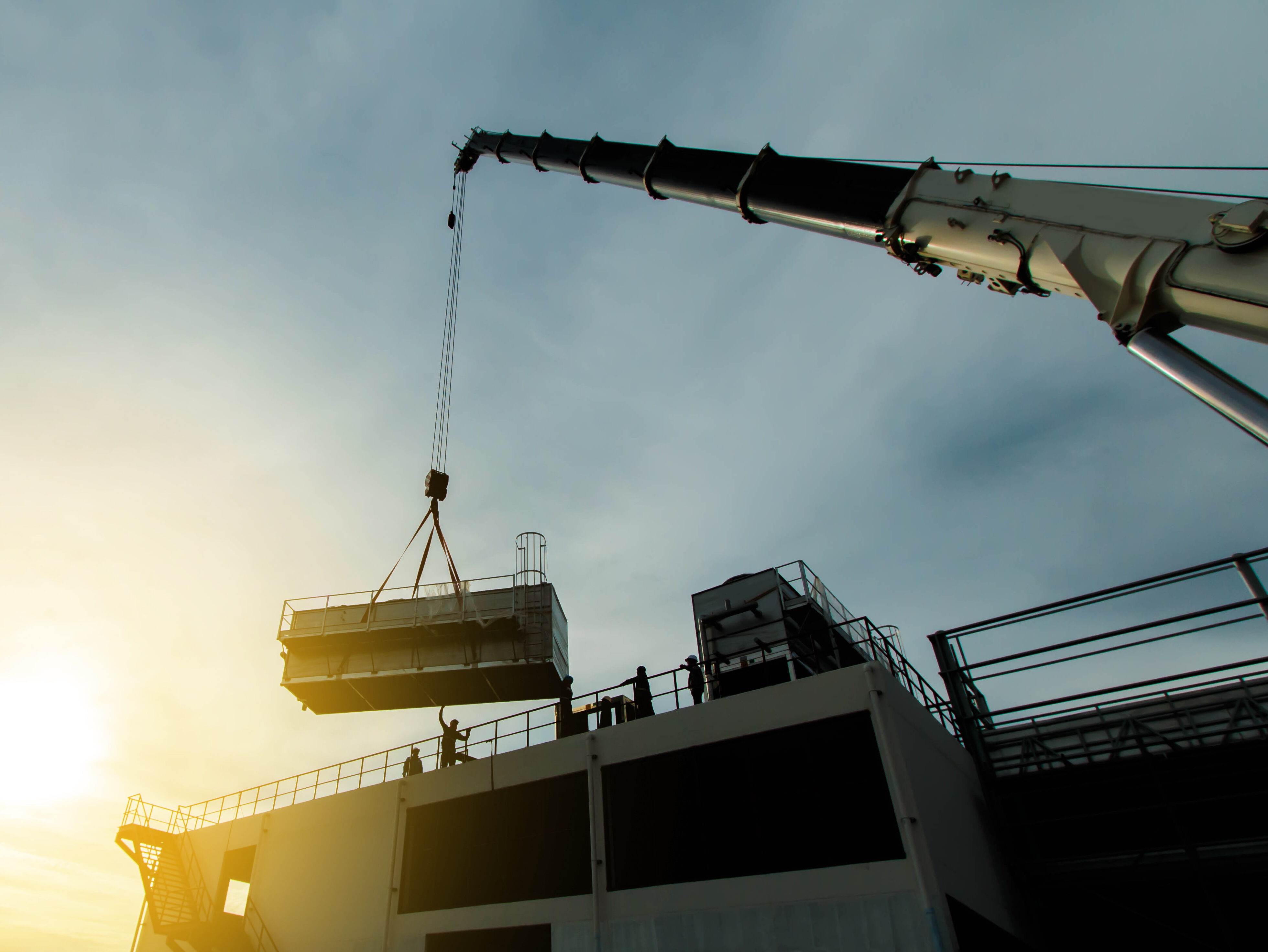 mobile crane lifting Cooling machine, silhouettes at sunset